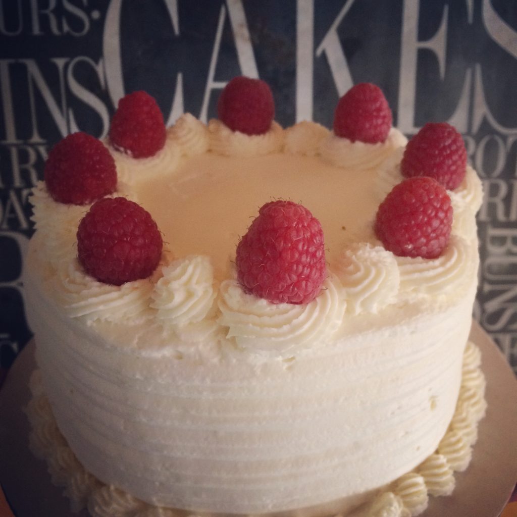 White cake made with wheat flower, raspberries on top of cake