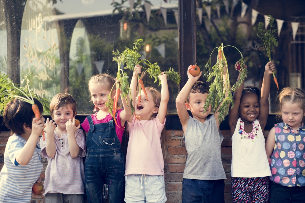 Young children holding fresh fruits and vegetables