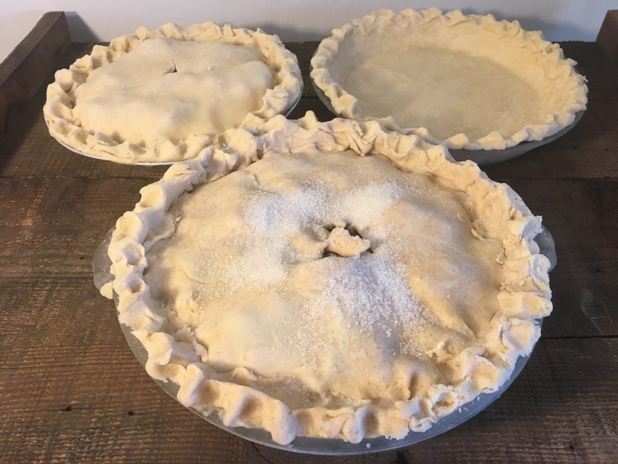 three uncooked pies with solid crusts