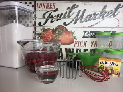 Freezer jam supplies: sugar, strawberries, Sure Jell, jars and whisk