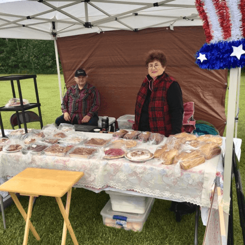 Woman and red plaid at her vendor booth selling breads and baked goods