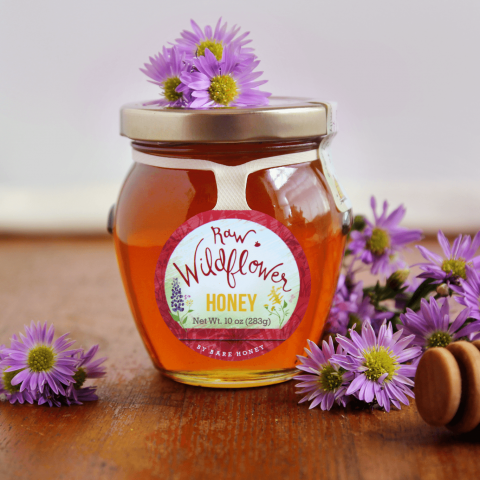 wildflower honey that is posed with wildflowers on wooden table