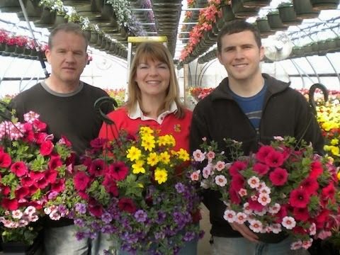 three people holding flower hanging baskets