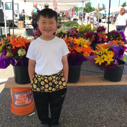 little boy smiling in front of flower display