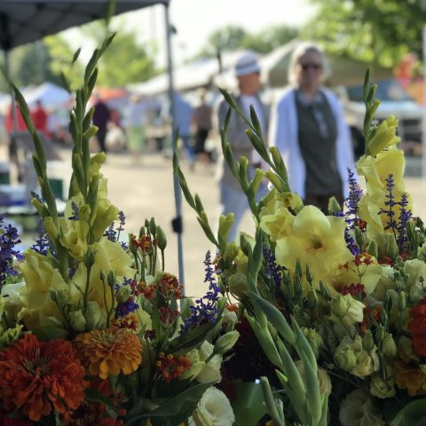 close up of flowers with farmers market scene in the background