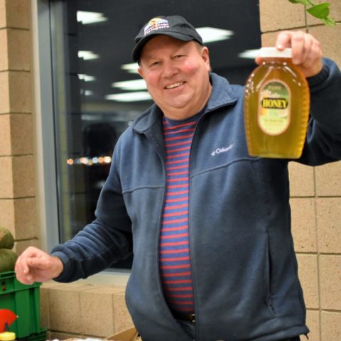 man holding up a jar of local honey