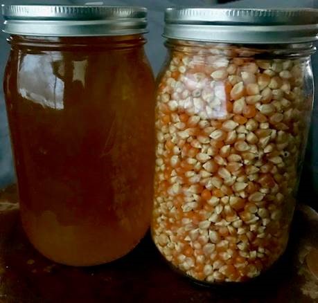 jar of honey next to a jar of corn kernels