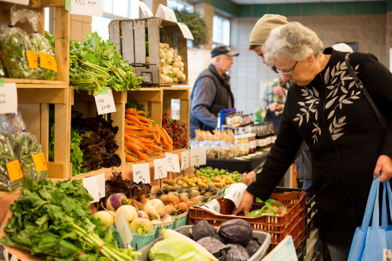 customers looking a large display of winter vegetables at indoor market