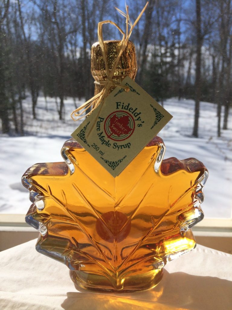 maple syrup bottle shaped like a maple leaf with snowy background