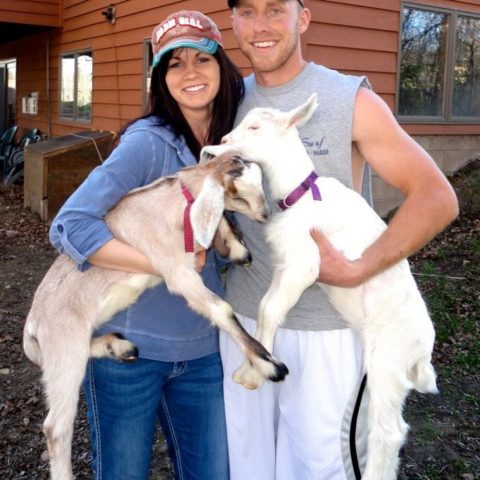 young couple holding two goats