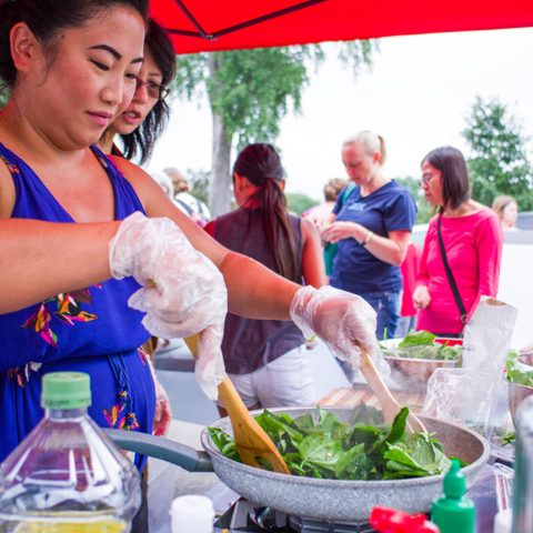 person cooking fresh greens at a market booth