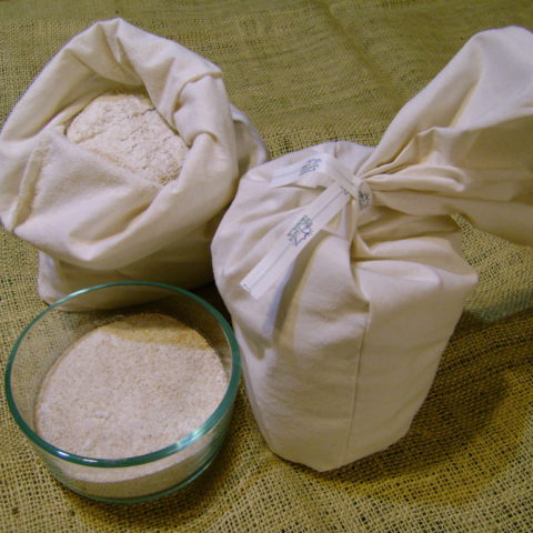 ground wheat in a bowl with small cloth flour bag