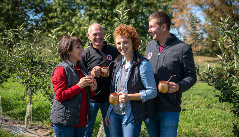The Redhead Creamery family standing amid apple trees.