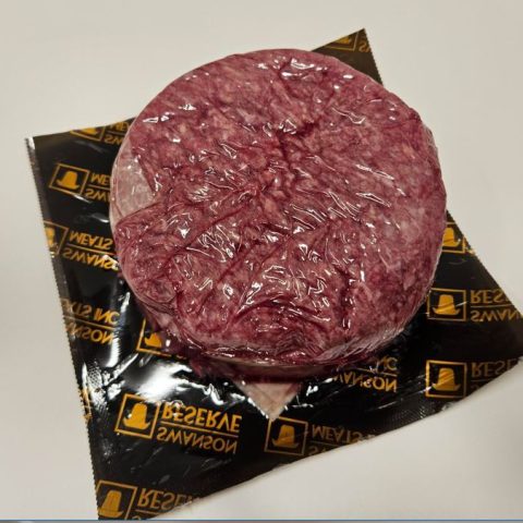 Packaged ground, raw meat in a circular shape.