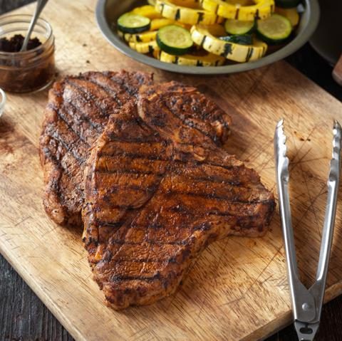 grilled tbone beef steak on a cutting board with tongs