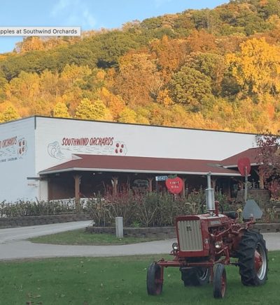 Southwind Orchards building with tractor in foreground and hills in fall colors in the background