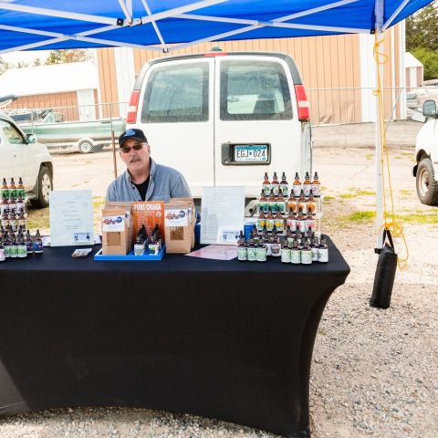 A vendor selling herbal tinctures at a farmers market.