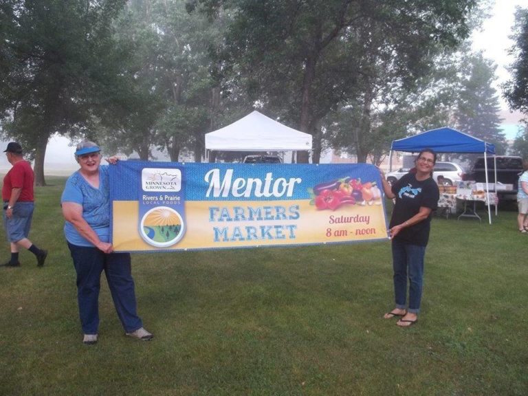 two people holding up a mentor farmers market banner