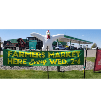 Picture of a green banner that says "Farmers Market Here Every Wed 2-6". The sign is outside in front of the Delano Farmers Market.