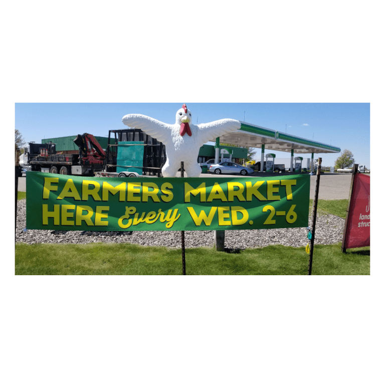 Picture of a green banner that says "Farmers Market Here Every Wed 2-6". The sign is outside in front of the Delano Farmers Market.