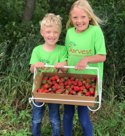 two children holding a freshly picked flat of berries