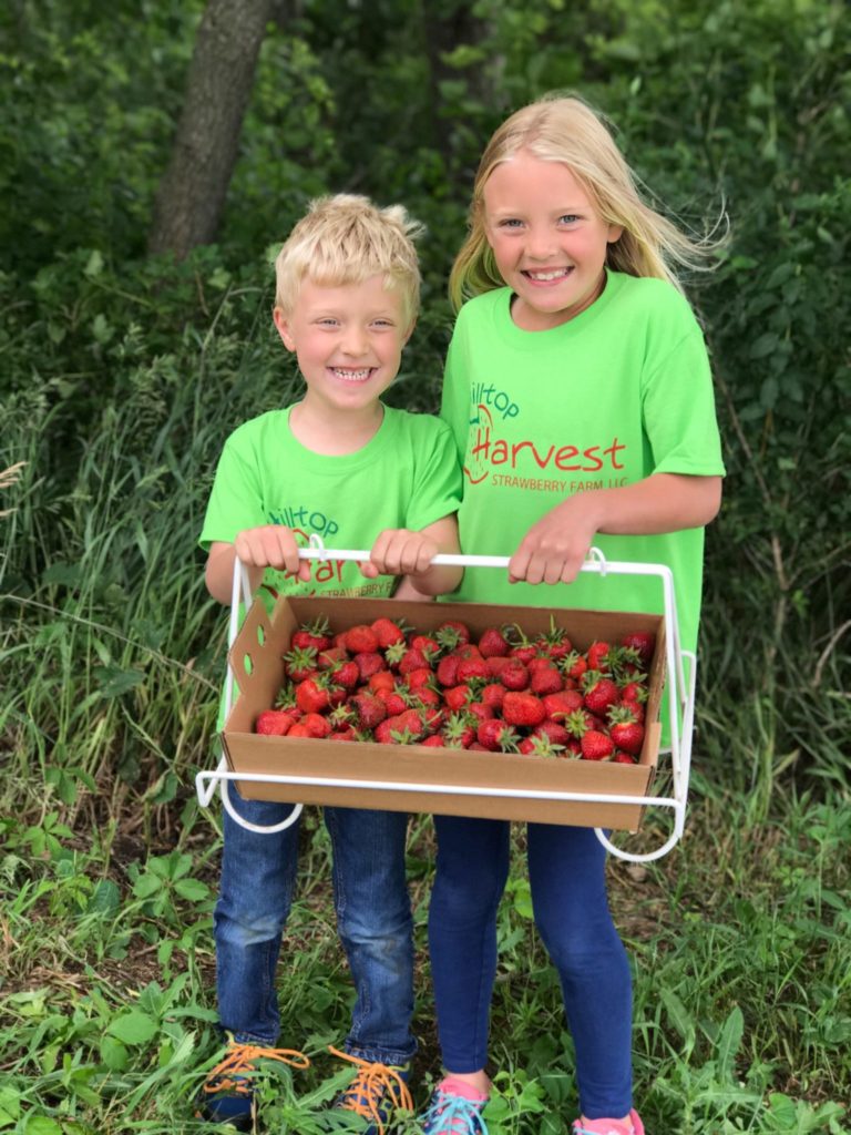 two children holding a freshly picked flat of berries