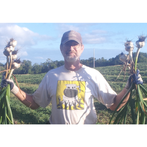 man holding up bunches of garlic