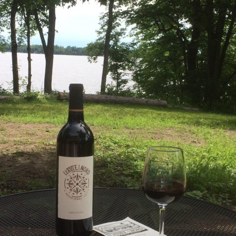 Bottle of wine and glass pictured in front of the lake.
