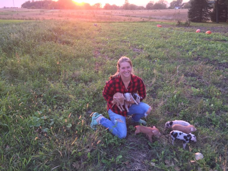 woman holding piglets in front of a sunset