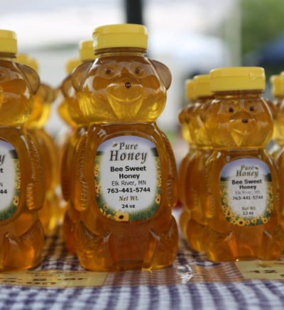 plastic honey bear of honey with label on a checkered table cloth