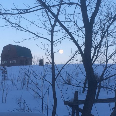 snowy hillside and barn under a full moon