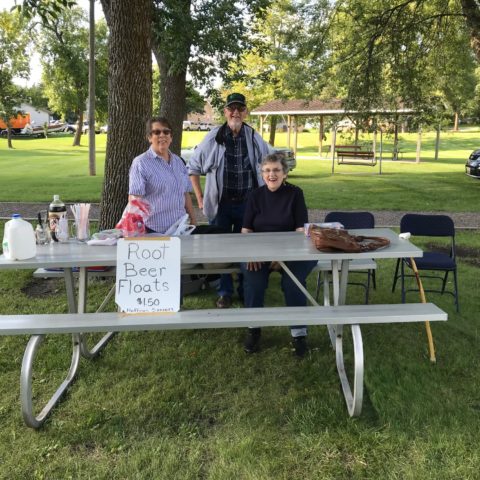 three people selling root beer floats at a table