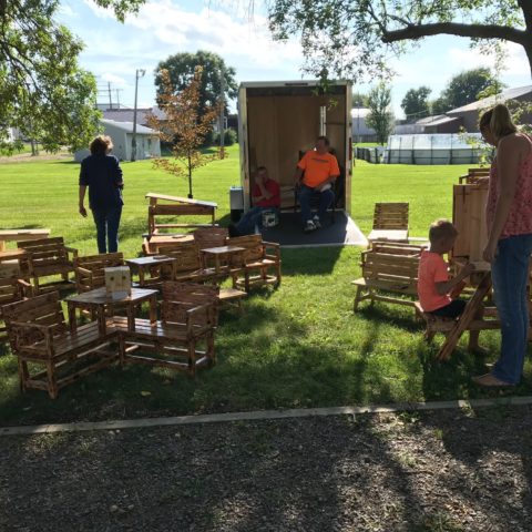 vendor selling wooden furniture at outdoor farmers market