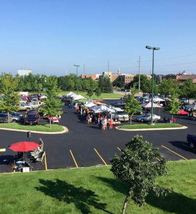 overview of outdoor market tents set up in a parking lot on a clear summer day