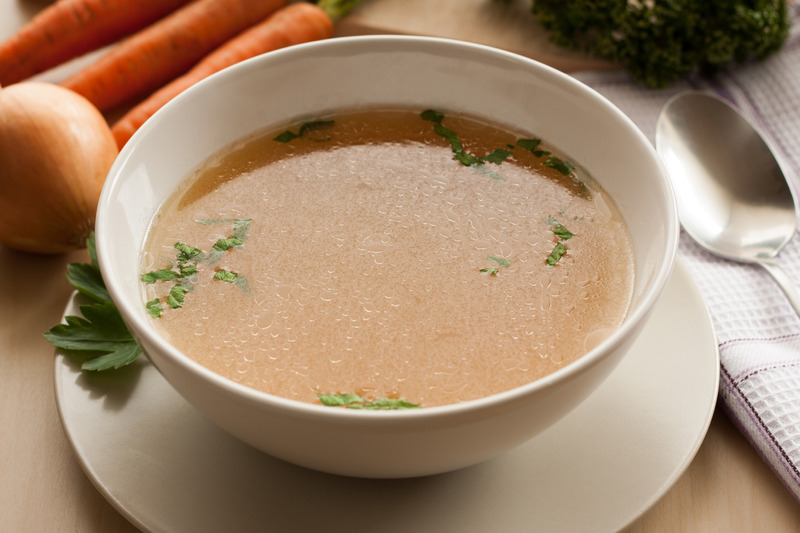 Bone broth made from chicken, served in a bowl with parsley