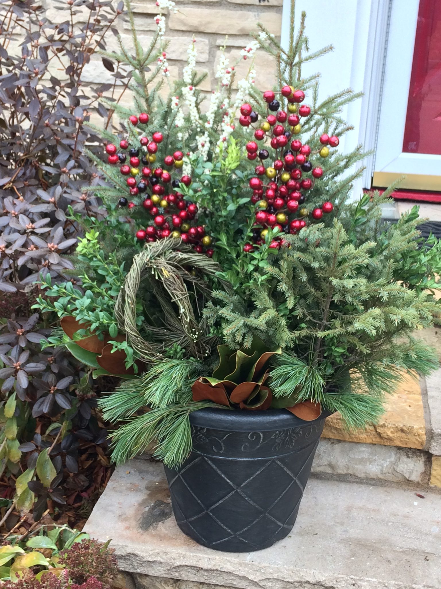 decorative pot with a variety of pine bows and red berries