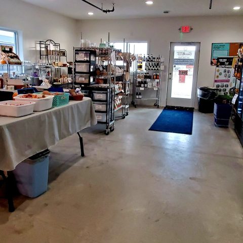 The inside of the Greensted store featuring concrete floors, shelves of products, and a table with more products.