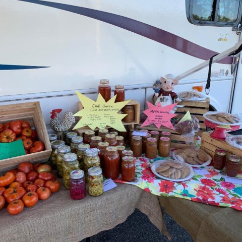 Fresh tomatoes, canned goods, and baked items on a market table