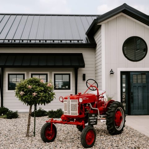 A vintage red tractor in front of a winery.
