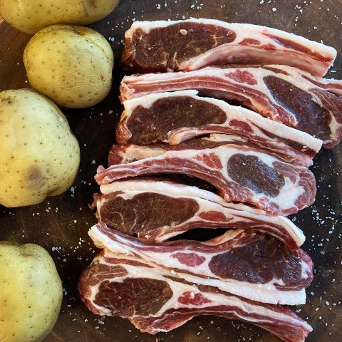 Potatoes and raw meat against a dark brown background.