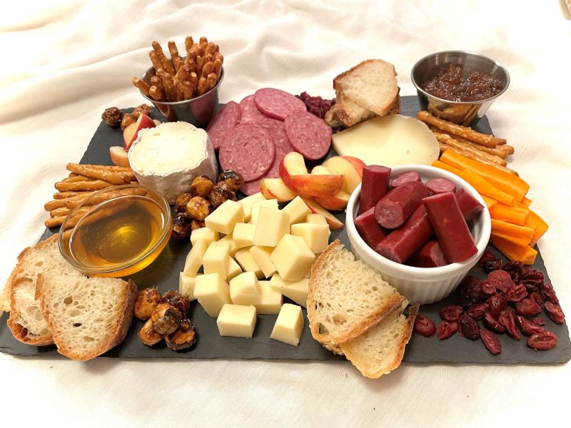 A meat and cheese board with honey, bread, jam etc.