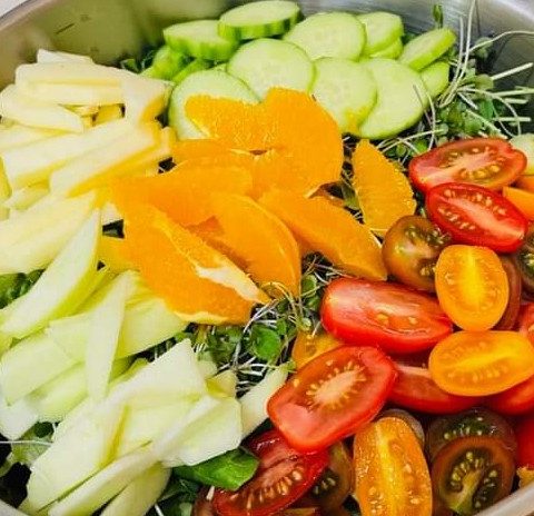 Picture of a bowl of fresh, cut vegetables. The bowl includes cherry tomatoes, yellow peppers, cucumbers, and more.