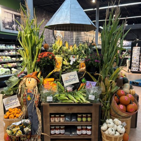 A grocery store produce display with ta farm theme with a corn silo and scarecrow.