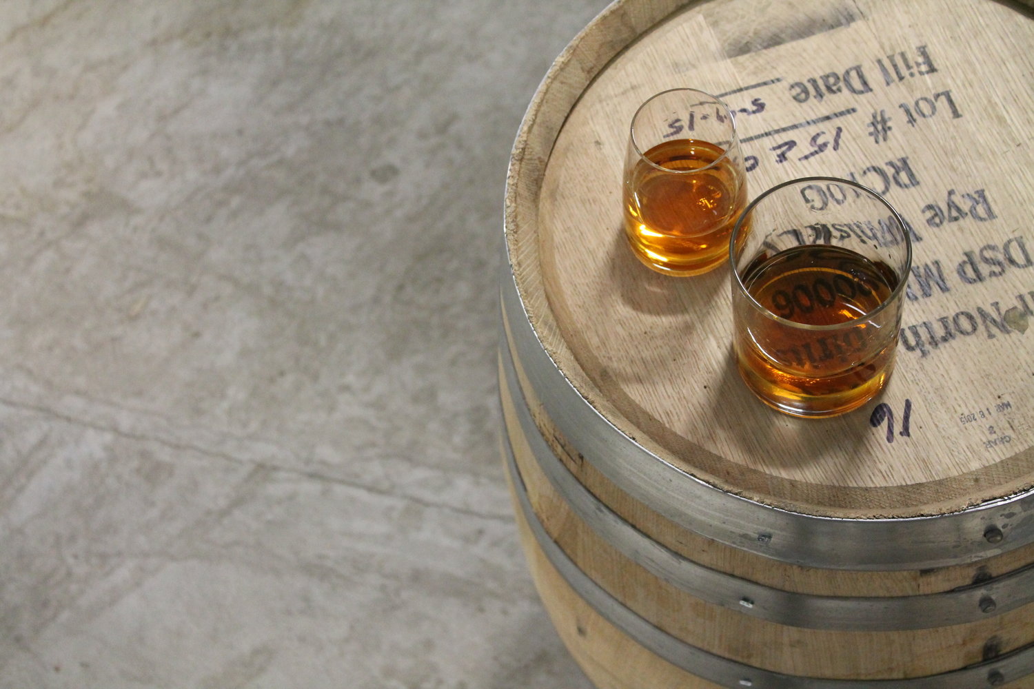 Two whiskey glasses on a barrel.