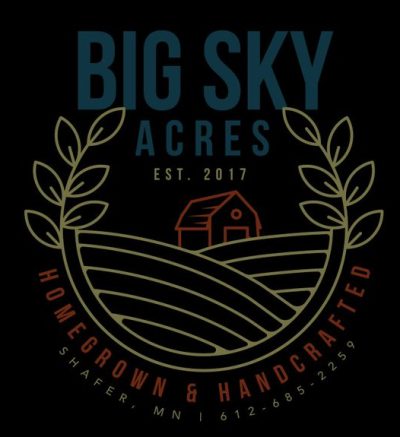 Logo with yellow and blue text that says "Big Sky Acres Est. 2017". The text is above a u-shaped vine with leaves at the ends. Inside the U is a drawing of a barn with a fields. Below the u is the text "Homegrown & Handcrafted Shafer, MN 612-685-2259" in red.