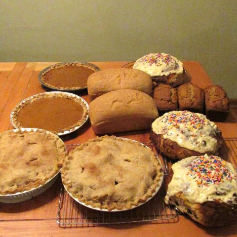 Array of pies and breads on a wood table.