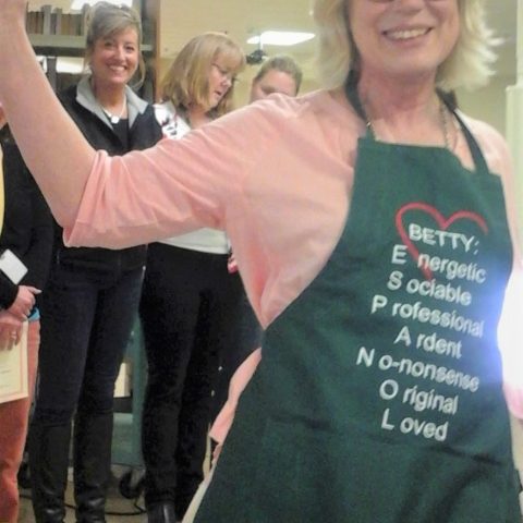 Picture of a woman smiling wearing an apron that says her name, "Betty".