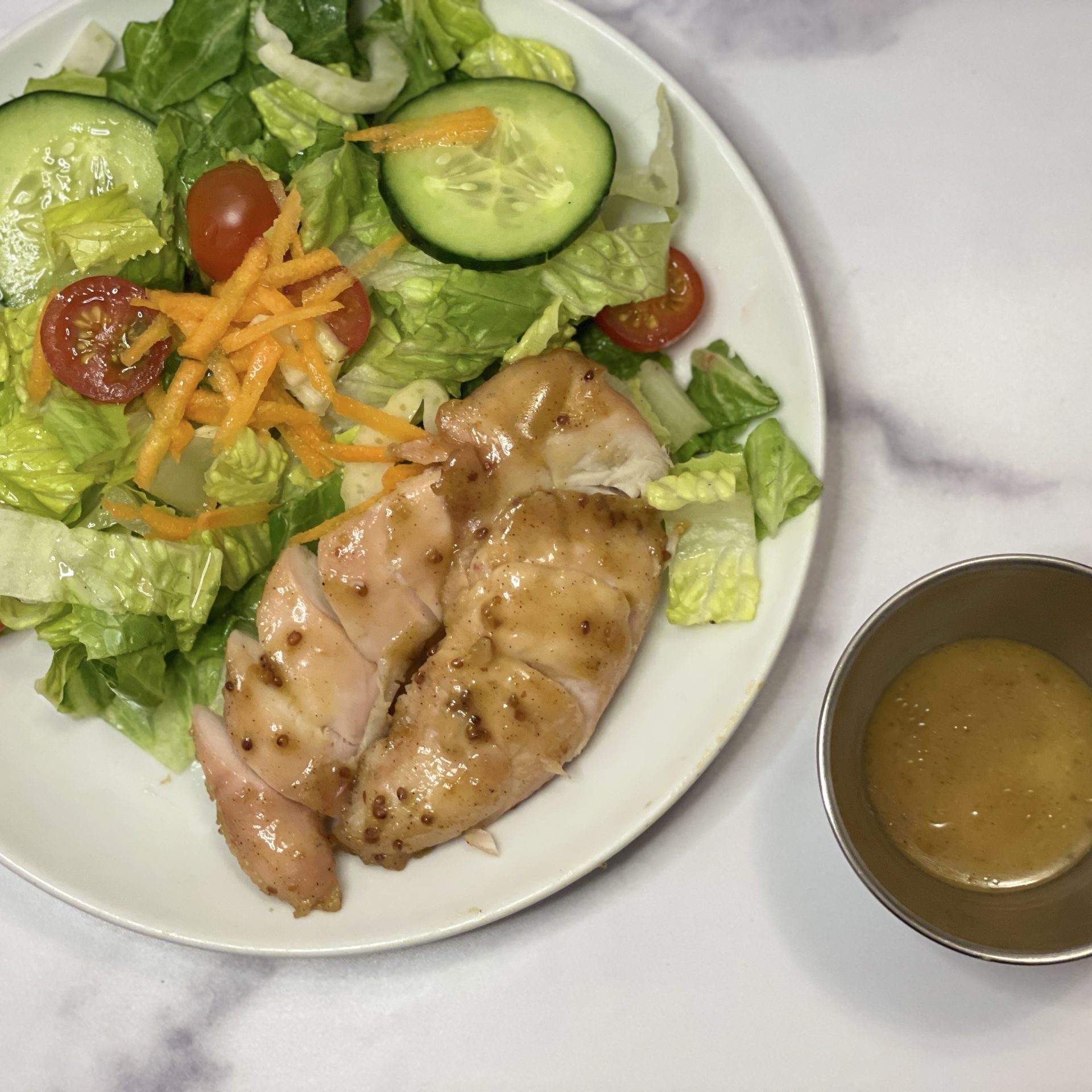A green salad with maple mustard glazed chicken.
