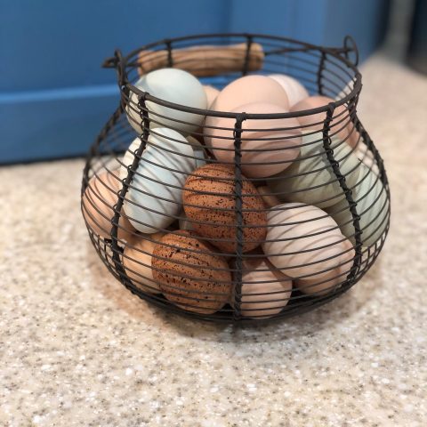 Black metal basket with multi-colored eggs inside.