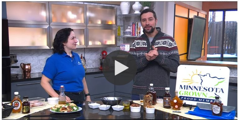 A woman on a tv set kitchen with a male host preparing a recipe with maple syrup.